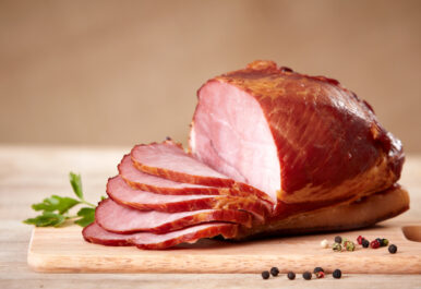 A ham on a cutting board. Half has been sliced. Photo by DepositPhotos
