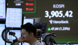 A currency trader watches monitors near a screen showing the Korea Composite Stock Price Index (KOSPI) at the foreign exchange dealing room of the Hana Bank headquarters in Seoul, South Korea, Wednesday, Nov. 26, 2025. (AP Photo/Ahn Young-joon)