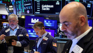FILE PHOTO: Traders work on the floor, as a screen displays The Goldman Sachs logo and trading information, at the New York Stock Exchange (NYSE) in New York City, U.S., April 14, 2025. REUTERS/Brendan McDermid/File Photo