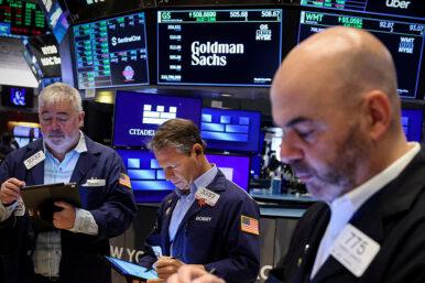 FILE PHOTO: Traders work on the floor, as a screen displays The Goldman Sachs logo and trading information, at the New York Stock Exchange (NYSE) in New York City, U.S., April 14, 2025. REUTERS/Brendan McDermid/File Photo