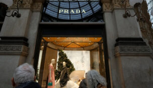 Customers look at a Prada shop window, in Milan, Italy, Tuesday, Dec. 2, 2025. (AP Photo/Luca Bruno)