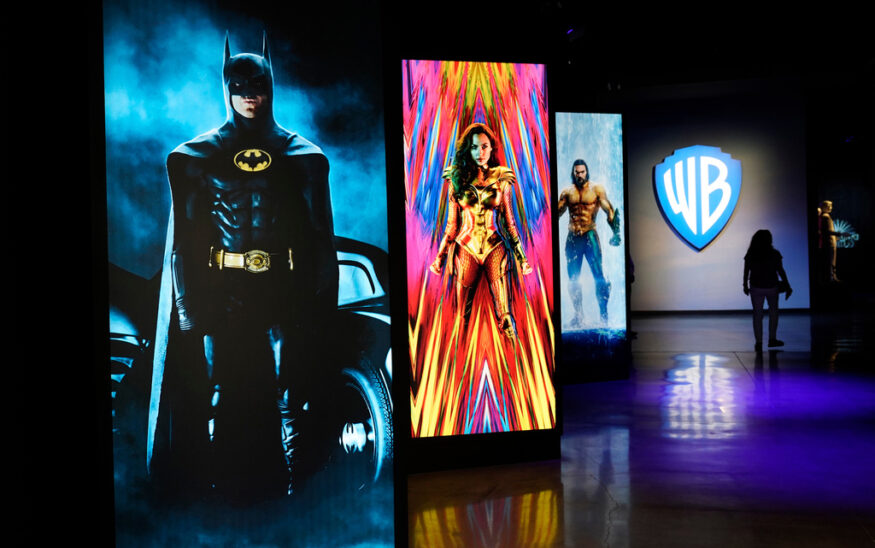 FILE - A visitor walks past portraits of DC Comics superheroes as she enters the "Action and Magic Made Here" interactive experience at the Warner Bros. Studio Tour Hollywood media preview on June 24, 2021, in Burbank, Calif. (AP Photo/Chris Pizzello, File)