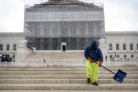 A worker shovels snow and ice in front of the Supreme Court building during the first snowfall of the winter season on Friday, Dec. 5, 2025, in Washington. (AP Photo/Mark Schiefelbein)