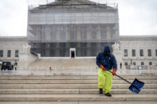 A worker shovels snow and ice in front of the Supreme Court building during the first snowfall of the winter season on Friday, Dec. 5, 2025, in Washington. (AP Photo/Mark Schiefelbein)