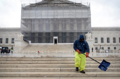 A worker shovels snow and ice in front of the Supreme Court building during the first snowfall of the winter season on Friday, Dec. 5, 2025, in Washington. (AP Photo/Mark Schiefelbein)