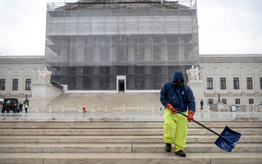 A worker shovels snow and ice in front of the Supreme Court building during the first snowfall of the winter season on Friday, Dec. 5, 2025, in Washington. (AP Photo/Mark Schiefelbein)