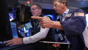 Specialist Glenn Carell, left, and trader Robert Charmak work on the floor of the New York Stock Exchange, Thursday, Dec. 11, 2025. (AP Photo/Richard Drew)