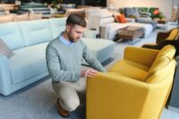 Young man looking for new chair for home at furniture warehouse. Photo: Depositphotos
