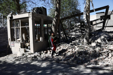 A man carries an Iranian flag as he walks amidst the rubble of a building of the Sharif University of Technology, which was damaged in a strike, amid the U.S.-Israeli conflict with Iran, in Tehran, Iran, April 7, 2026. Majid Asgaripour/WANA (West Asia News Agency) via REUTERS