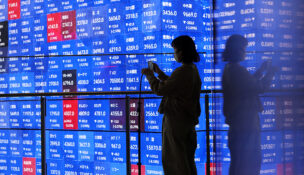 A visitor stands next to an electronic screen displaying Japan's Nikkei stock prices quotation board inside a conference hall in Tokyo, Japan March 4, 2026. REUTERS/Issei Kato/ File Photo