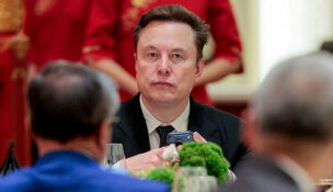 Tesla CEO Elon Musk holds a mobile phone as he arrives to attend a state banquet with U.S. President Donald Trump and Chinese President Xi Jinping at the Great Hall of the People in Beijing, China, May 14, 2026. REUTERS/Evan Vucci//File Photo