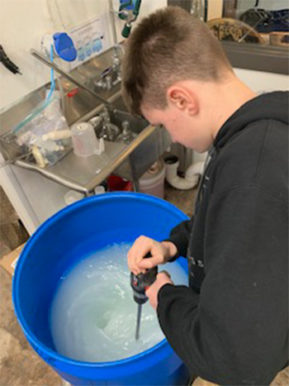 John B. Davenport's son Jack Davenport mixing the hand sanitizer ingredients. John Davenport is the head distiller and co-founder of Three Crosses Distilling. 